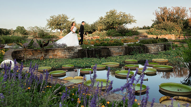 Newly wed man and woman walking accross a pond